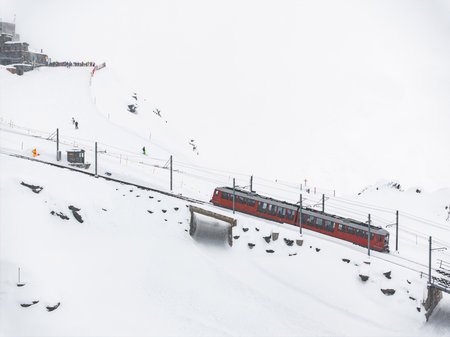 Aerial View of Red Train in Snowy Zermatt, Switzerland with Skiers in Background
