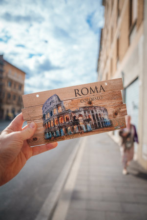 Hand holding Rome Colosseum postcard, wooden background.の写真素材