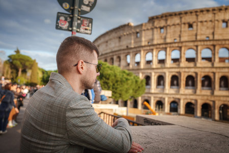 Man in Plaid Jacket Leaning on Stone Ledge at Colosseum, Rome