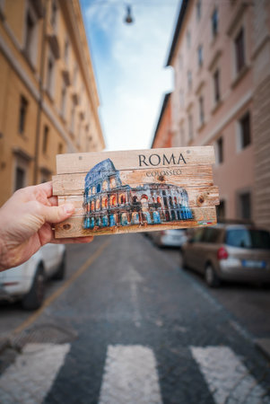 Hand holding vintage Colosseum wood art in Rome street.