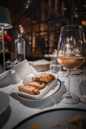 Refined dining setting with white wine, bread, and elegant decor.