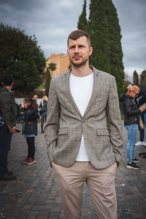 Smart Casual Man in Plaid Blazer Standing Outdoors, European City Vibe
