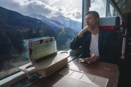 Man in Casual Blazer Enjoying Train Ride Through Scenic Mountains