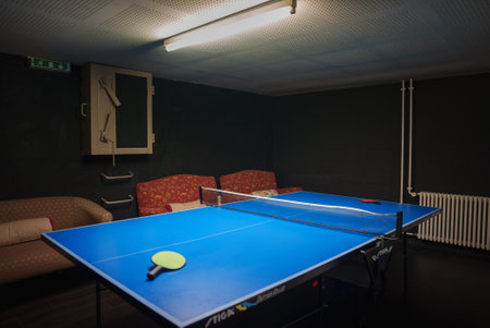 Recreational Setup with Table Tennis, Chairs, and Exit Sign in Dark Roomの写真素材