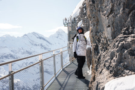 Man in Winter Gear Standing on Metal Walkway Over Swiss Alps