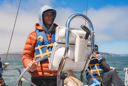 Boat captain in red jacket guides ship near San Francisco Coast.の写真素材
