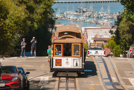 San Francisco cable car travels on steep street, by bay.
