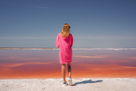 Surreal scene of person in pink dress at Alviso Pink Lake, Californiaの写真素材