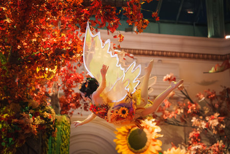 Whimsical indoor scene in Las Vegas, displaying a fairy like figure with floral costume and translucent wings surrounded by autumn foliage and magical lighting.の写真素材