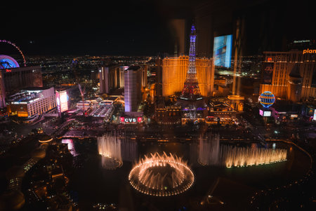 Vibrant Las Vegas Strip night scene with Bellagio fountains lit up and shooting water high, Eiffel Tower replica, glowing lights, and lively atmosphere.の写真素材