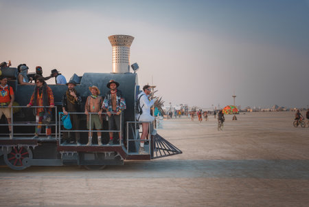 Scene of music and art festival in expansive desert. Festive group on art car resembling vintage...