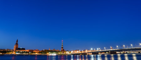 Illuminated Night View of Riga with Daugava River and Notable Landmarksの写真素材