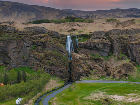 Aerial View of Majestic Waterfall Cascading Down Rocky Cliff in Icelandの写真素材