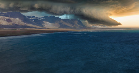 Dramatic Storm Clouds Over Snow-Capped Mountains and Calm Ocean in Iceland