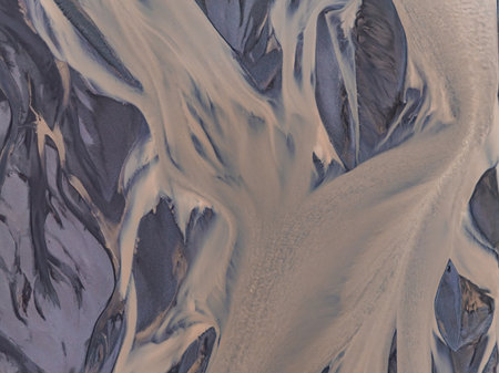Aerial View of Meandering River Through Dark Gray Landscape in Iceland