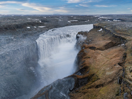 Aerial View of Majestic Waterfall Cascading Down Rocky Cliff in Icelandの写真素材