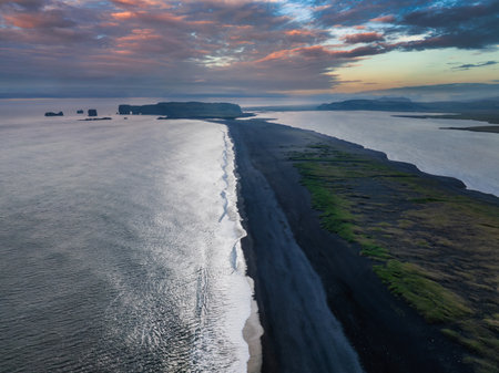 Aerial View of Black Sand Beach and Rocky Peninsula in Iceland at Sunset