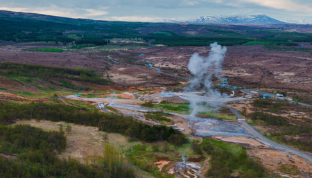 Aerial View of Erupting Geyser in Icelandic Valley Surrounded by Hillsの写真素材