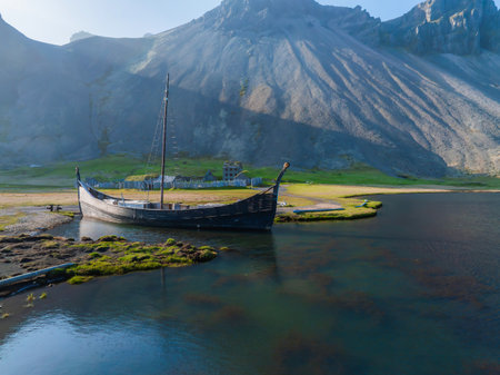 Wooden Longboat in Calm Waters of Icelandic Fjord with Volcanic Mountains