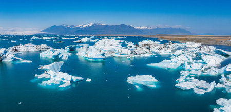 Aerial View of Glacial Lagoon with Snow-Capped Mountains in Icelandの写真素材