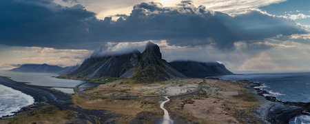 Aerial View of Icelandic Valley with Winding Road and Volcanic Beachの写真素材