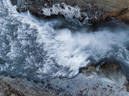 Aerial View of Powerful Waterfall Cascading Over Rugged Rocks in Iceland