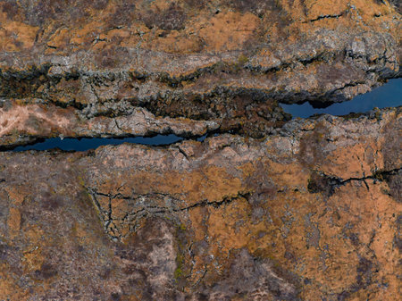 Aerial View of a Deep Earth Crack with Narrow Stream in Volcanic Terrainの写真素材