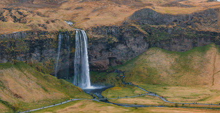 Aerial View of Majestic Waterfall Cascading Down Steep Cliff in Icelandの写真素材
