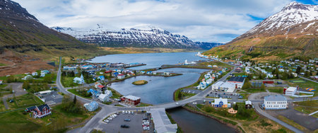 The aerial view of a town in Iceland showcases a picturesque landscape with houses, mountains, and a lake.の写真素材