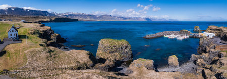 Aerial View of Rocky Icelandic Coastline with White House and Harbor