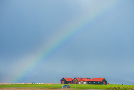 Charming Red Roof House with Rainbow in Serene Icelandic Landscapeの写真素材