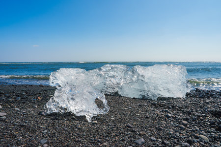 Serene Coastal Scene with Ice Chunks on Black Pebble Beach at Diamond Beach, Icelandの写真素材
