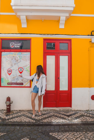Woman Pointing at Tourist Map on Bright Yellow Building in Aveiro, Portugalの写真素材