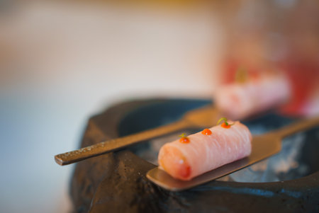 Close-Up of Elegantly Presented Sushi Rolls on Sleek Metal Utensilsの写真素材
