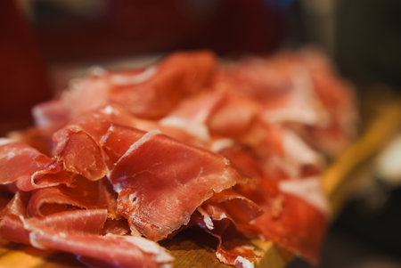 Close-Up of Thinly Sliced Prosciutto on Wooden Board in Luxury Settingの写真素材