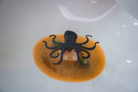 Exquisitely Plated Seafood Dish with Octopus Garnish in Luxury Hotel Restaurantの写真素材