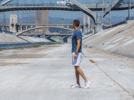 Person in Los Angeles River Channel with Bridges and Mountainsの写真素材
