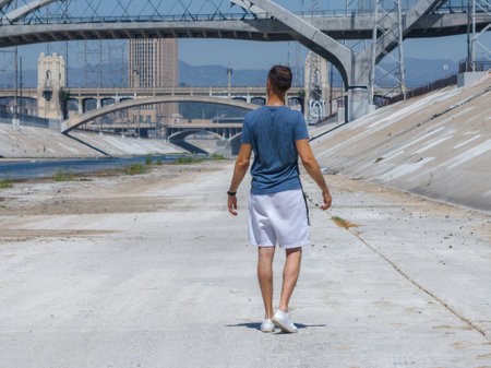Person Walking Along Los Angeles River with Iconic Arched Bridgesの写真素材