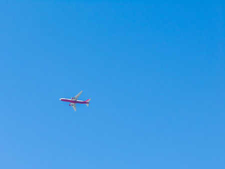 Red and White Airplane Flying Against Clear Blue Skyの写真素材