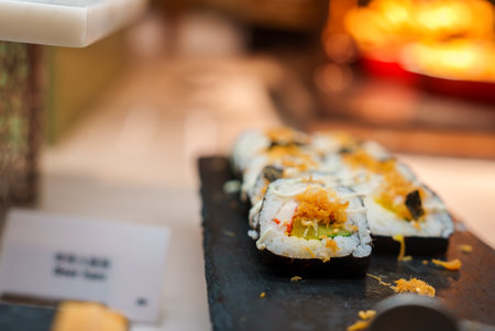 Close Up of Sushi Rolls with Golden Garnish on Slate Boardの写真素材
