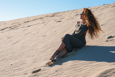 Woman Sitting on Sand Dune Under Clear Sky in Tarifa, Spainの写真素材