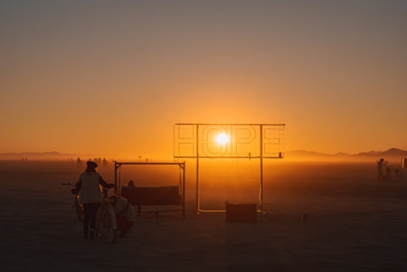 Sunset Behind HOPE Installation at Desert Festival with Silhouettesの写真素材