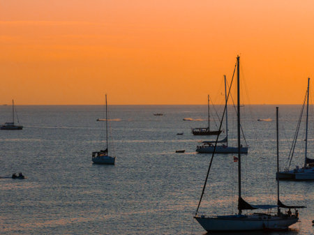 Serene Sunset Over Beach with Anchored Sailboats