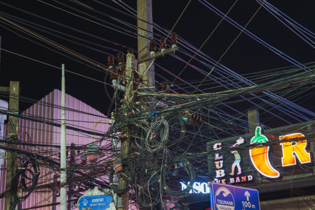 Tangled Electrical Wires and Neon Signs at Night in Phuket, Thailandの写真素材