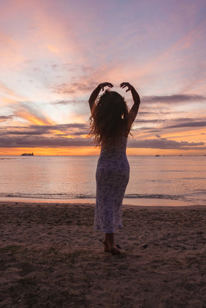 Woman Silhouetted on a Sandy Beach at Sunset with Vibrant Sky