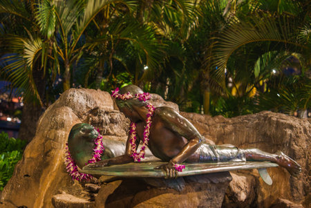 Bronze Surfer Statue with Flower Leis in Tropical Night Settingの写真素材