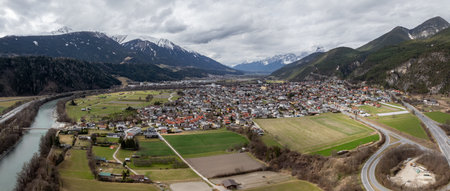 Small Town in the Austrian Alps with River and Snow Capped Mountainsの写真素材