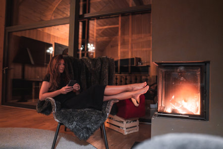 Luxury Hotel Interior with Woman Relaxing by Fireplace in Italian Alpsの写真素材