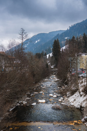Mountain Stream and Snowy Slopes in the Alps During Winterの写真素材