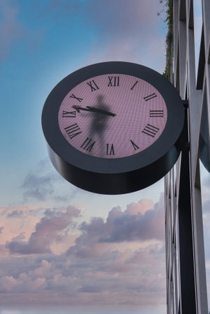 Large Pink Clock with Roman Numerals on Modern London Buildingの写真素材